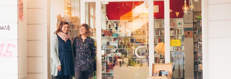 Marietta Bernasconi und Anna Wallitzer stehen draußen vor der Ladentür der Buchhandlung