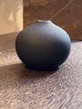Schwarze Perlenvase mit einer schmalen Öffnung die in eine kugelförmige Schale übergeht