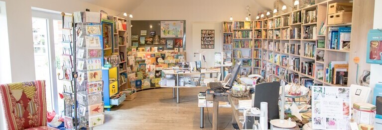 Blick von der Ladentür in die Buchhandlung, man sieht Büchertische, einen Tresen und Bücherregale