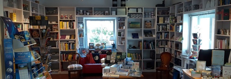 Blick in den hinteren Raum der Buchhandlung mit den diversen Abteilungen und einem rotem Sofa vor dem Fenster
